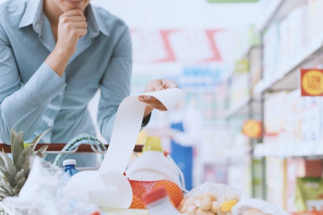 woman looking at long grocery receipt